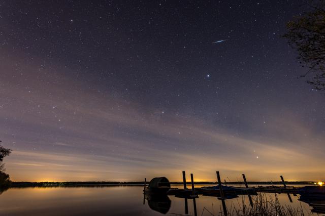 23 April 2026, Brandenburg, Neuhausen: A shooting star of the Lyrids can be seen in the night sky above the Spremberg reservoir. Every year in April, the earth passes through the dust trail of comet C/1861 GA Thatcher. Photo: Frank Hammerschmidt/dpa