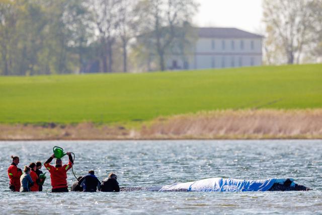 23 April 2026, Mecklenburg-Vorpommern, Fährdorf: Rescuers stand in close proximity to a humpback whale off the coast of Poel Island, tending to the animal as it remains stuck in shallow water three weeks after stranding near Wismar, despite ongoing rescue efforts by a private initiative. Photo: Jens Büttner/dpa