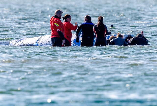 23 April 2026, Mecklenburg-Vorpommern, Fährdorf: Rescuers stand in close proximity to a humpback whale off the coast of Poel Island, tending to the animal as it remains stuck in shallow water three weeks after stranding near Wismar, despite ongoing rescue efforts by a private initiative. Photo: Jens Büttner/dpa