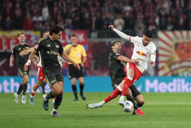 24 April 2026, Saxony, Leipzig: (L-R) Union Berlin's Diogo Leite, Union Berlin's Rani Khedira, and Leipzig's Romulo battle for the ball during the German Bundesliga soccer match between RB Leipzig and 1. FC Union Berlin at Red Bull Arena. Photo: Jan Woitas/dpa - IMPORTANT NOTICE: DFL and DFB regulations prohibit any use of photographs as image sequences and/or quasi-video.