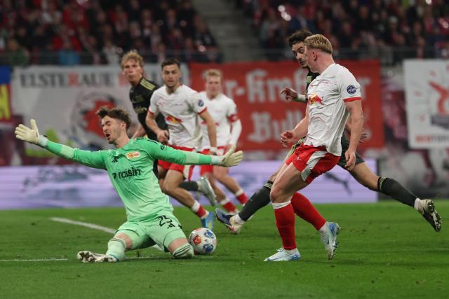 24 April 2026, Saxony, Leipzig: (R-L) Leipzig's Conrad Harder and Union Berlin's Diogo Leite battle for the ball alongside Union Berlin goalkeeper Carl Klaus during the German Bundesliga soccer match between RB Leipzig and 1. FC Union Berlin at Red Bull Arena. Photo: Jan Woitas/dpa - IMPORTANT NOTICE: DFL and DFB regulations prohibit any use of photographs as image sequences and/or quasi-video.