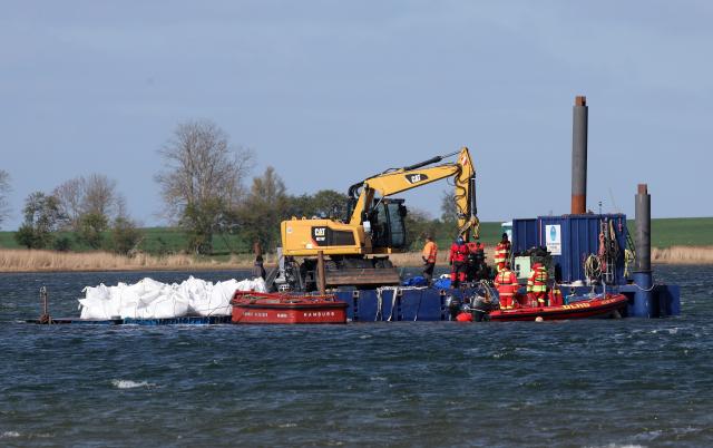 25 April 2026, Mecklenburg-Western Pomerania, Faehrdorf: A floating platform with dozens of big bags filled with sand is towed to the working platform next to the stranded humpback whale off the Baltic Sea island of Poel. A private initiative has been trying to rescue the stranded humpback whale that is still lying in shallow water. Photo: Bernd Wüstneck/dpa