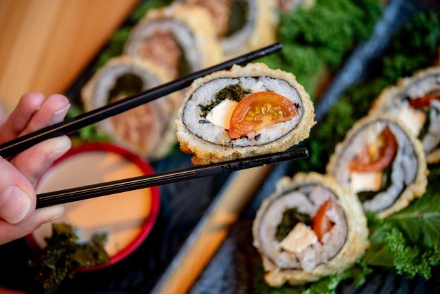 FILED - 07 November 2023, Lower Saxony, Oldenburg: A woman holds sushi with her chopsticks in a restaurant. Photo: Hauke-Christian Dittrich/dpa