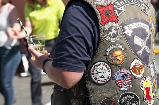 25 April 2026, Bavaria, Kulmbach: A visitor at the motorcycle rally wears a leather jacket and holds a drink as enthusiasts gather under the motto "Arrive, don't perish" for the 23rd Kulmbach Motorcycle Rally on the grounds of the Kulmbach Brewery. Photo: Daniel Vogl/dpa