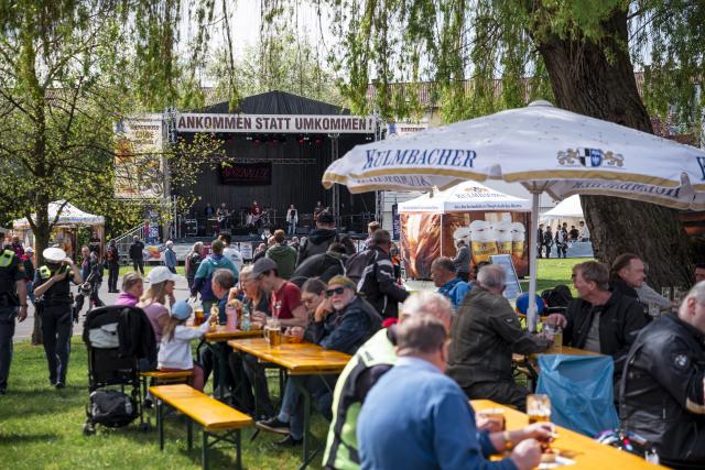 25 April 2026, Bavaria, Kulmbach: Visitors sit on the grounds of the Kulmbach Brewery, enjoying drinks and musical entertainment during the 23rd Kulmbach Motorcycle Rally, held under the motto "Arrive, don't perish." Photo: Daniel Vogl/dpa