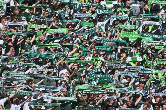 25 April 2026, Lower Saxony, Wolfsburg: Wolfsburg fans hold up numerous green-and-white scarves ahead of the German Bundesliga soccer match between VfL Wolfsburg and Borussia Moenchengladbach at the Volkswagen Arena. Photo: Swen Pförtner/dpa - IMPORTANT NOTE: In accordance with the regulations of the DFL German Football League and the DFB German Football Association, it is prohibited to utilize or have utilized photographs taken in the stadium and/or of the match in the form of sequential images and/or video-like photo series.