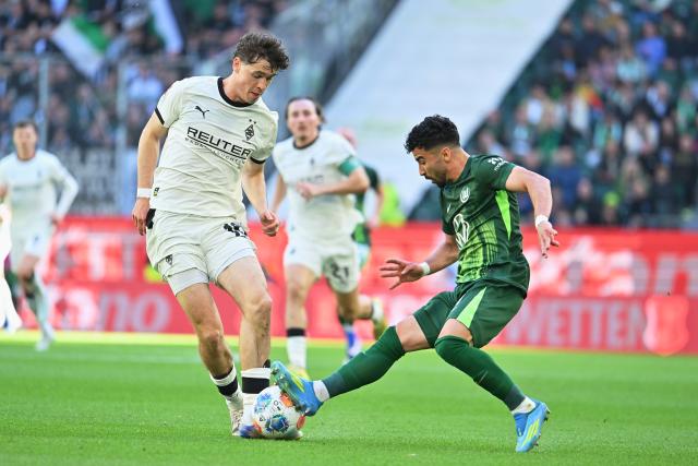 25 April 2026, Lower Saxony, Wolfsburg: Wolfsburg's Mohamed Amoura (R) and Moenchengladbach's Philipp Sander (L) battle for the ball during the German Bundesliga soccer match between VfL Wolfsburg and Borussia Moenchengladbach at the Volkswagen Arena. Photo: Swen Pförtner/dpa - IMPORTANT NOTE: In accordance with the regulations of the DFL German Football League and the DFB German Football Association, it is prohibited to utilize or have utilized photographs taken in the stadium and/or of the match in the form of sequential images and/or video-like photo series.
