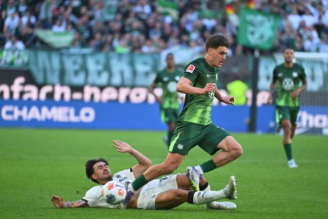 25 April 2026, Lower Saxony, Wolfsburg: Wolfsburg's Dzenan Pejcinovic (R) and Borussia Moenchengladbach's Tobias Sippel (L) battle for the ball during the German Bundesliga soccer match between VfL Wolfsburg and Borussia Moenchengladbach at the Volkswagen Arena. Photo: Swen Pförtner/dpa - IMPORTANT NOTE: In accordance with the regulations of the DFL German Football League and the DFB German Football Association, it is prohibited to utilize or have utilized photographs taken in the stadium and/or of the match in the form of sequential images and/or video-like photo series.