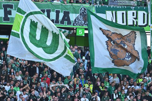 25 April 2026, Lower Saxony, Wolfsburg: VfL Wolfsburg fans wave large flags in the stands during the German Bundesliga soccer match between VfL Wolfsburg and Borussia Moenchengladbach at the Volkswagen Arena. Photo: Swen Pförtner/dpa - IMPORTANT NOTE: In accordance with the regulations of the DFL German Football League and the DFB German Football Association, it is prohibited to utilize or have utilized photographs taken in the stadium and/or of the match in the form of sequential images and/or video-like photo series.