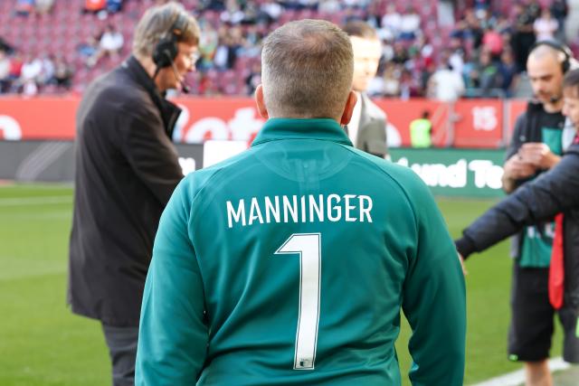 25 April 2026, Bavaria, Augsburg: Augsburg coach Manuel Baum is wearing a 'Manninger' jersey in memory of former Augsburg goalkeeper Alex Manninger, who died in an accident on April 16, 2026 during the German Bundesliga soccer match between FC Augsburg and Eintracht Frankfurt at WWK-Arena. Photo: Daniel Löb/dpa - WICHTIGER HINWEIS: Gemäß den Vorgaben der DFL Deutsche Fußball Liga bzw. des DFB Deutscher Fußball-Bund ist es untersagt, in dem Stadion und/oder vom Spiel angefertigte Fotoaufnahmen in Form von Sequenzbildern und/oder videoähnlichen Fotostrecken zu verwerten bzw. verwerten zu lassen.
