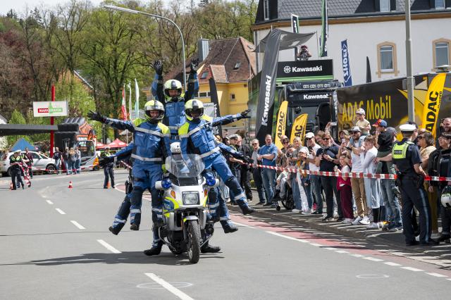 25 April 2026, Bavaria, Kulmbach: In the Munich Police Motorcycle Stunt Show, seven police officers perform stunts on a single motorcycle during the 23rd Kulmbach Motorcycle Rally, held under the motto "Arrive Safely, Don't Get Killed" at the Kulmbach Brewery grounds. Photo: Daniel Vogl/dpa