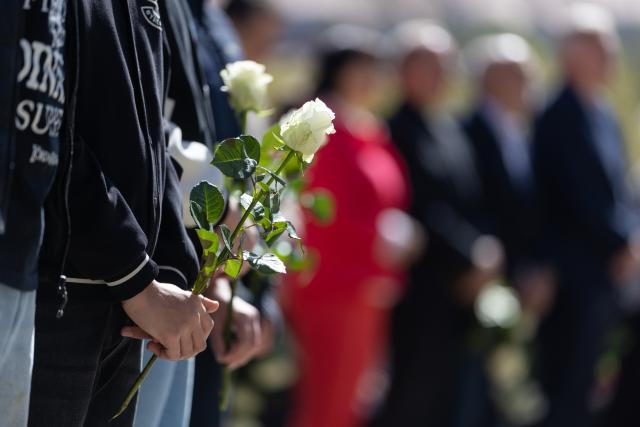 26 April 2026, Thuringia, Erfurt: Pupils hold flowers at the memorial service for the school massacre at Erfurt's Gutenberg Grammar School. On April 26, 2002, a 19-year-old former pupil of the grammar school shot twelve teachers, two pupils, a secretary and a policeman and then killed himself. Photo: Michael Reichel/dpa