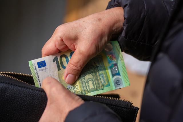 FILED - 24 March 2026, Berlin: A senior citizen puts euro banknotes in a purse. Photo: Fernando Gutierrez-Juarez/dpa