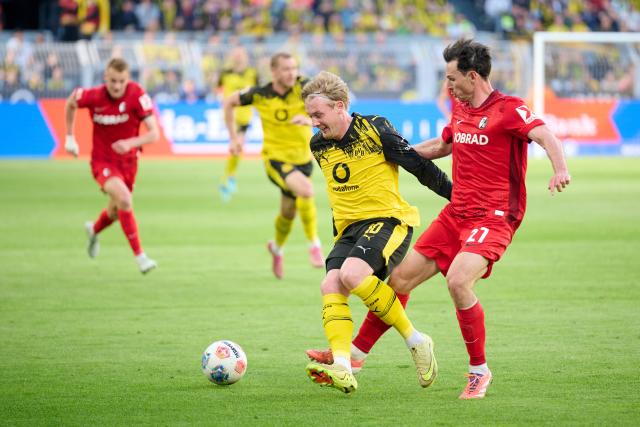 26 April 2026, North Rhine-Westphalia, Dortmund: Borussia Dortmund's Julian Brandt (L) and Freiburg's Nicolas Hoefler battle for the ball during the German Bundesliga soccer match between Borussia Dortmund and SC Freiburg at Signal Iduna Park. Photo: Bernd Thissen/dpa - WICHTIGER HINWEIS: Gemäß den Vorgaben der DFL Deutsche Fußball Liga bzw. des DFB Deutscher Fußball-Bund ist es untersagt, in dem Stadion und/oder vom Spiel angefertigte Fotoaufnahmen in Form von Sequenzbildern und/oder videoähnlichen Fotostrecken zu verwerten bzw. verwerten zu lassen.