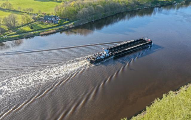 26 April 2026, Schleswig-Holstein, Hohenhoern: A barge, pushed by the pusher tug "Hans," is traveling along the Kiel Canal near Hohenhoern. The barge, which is intended to transport the whale from the Baltic Sea to the North Sea, is expected to arrive at the island of Poel tonight or early Monday morning. Photo: Bodo Marks/dpa