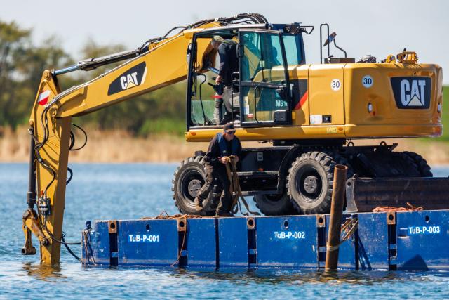 26 April 2026, Mecklenburg-Western Pomerania, Faehrdorf: An excavator on a pontoon is preparing the seabed for the recovery of the stranded humpback whale off the coast of Poel Island. The humpback whale, which is about twelve meters long, is to be rescued using a barge. Photo: Jens Büttner/dpa