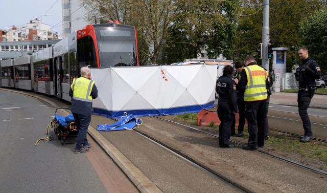 27 April 2026, Bremen: Police officers stand in front of a privacy screen following a serious accident involving a BSAG tram. A pedestrian was killed in the accident. Photo: Jörn Hüneke/dpa