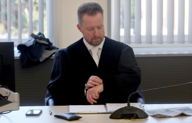 28 April 2026, Mecklenburg-Western Pomerania, Rostock: Harald Nowack, senior public prosecutor, looks at his watch in the courtroom of the regional court before the start of the murder trial in the Fabian case. The 30-year-old defendant is accused of killing eight-year-old Fabian from Güstrow on October 10, 2025 in a dastardly manner and with base motives. Photo: Bernd Wüstneck/dpa