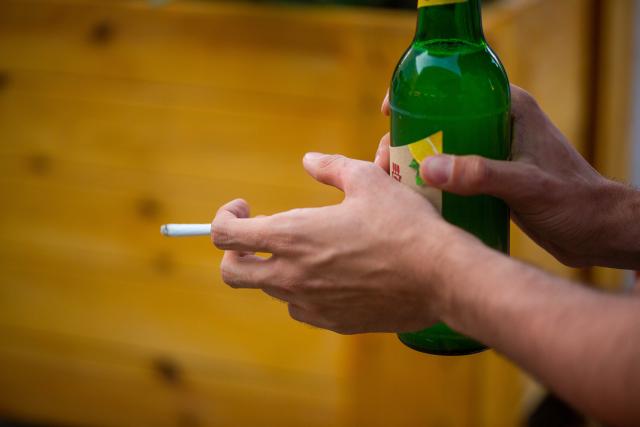 FILED - 10 July 2023, Berlin: A man holds a lit cigarette and a Radler beer bottle in his hands. Photo: Fernando Gutierrez-Juarez/dpa