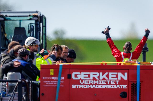 28 April 2026, Mecklenburg-Western Pomerania, Faehrdorf: Rescuers celebrate on the transport ship after the stranded humpback whale off the island of Poel was pulled onto the barge using straps. The humpback whale, which stranded near Wismar over three weeks ago, is now to be transported by ship to the North Sea. Photo: Jens Büttner/dpa