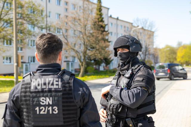 28 April 2026, Saxony, Neustadt: Police officers stand near the scene of the crime after gunshots in the vicinity of an apartment building. Police discovered two dead and one seriously injured person. Photo: Jürgen Lösel/dpa