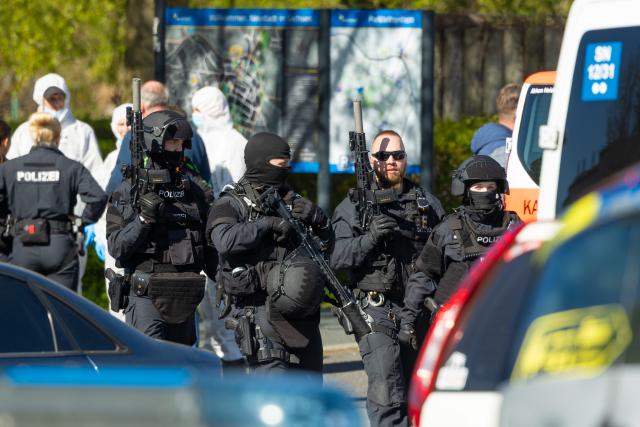 28 April 2026, Saxony, Neustadt: Police officers and forensic investigators stand near the scene of the crime after gunshots in the vicinity of an apartment building. Police discovered two dead and one seriously injured person. Photo: Jürgen Lösel/dpa