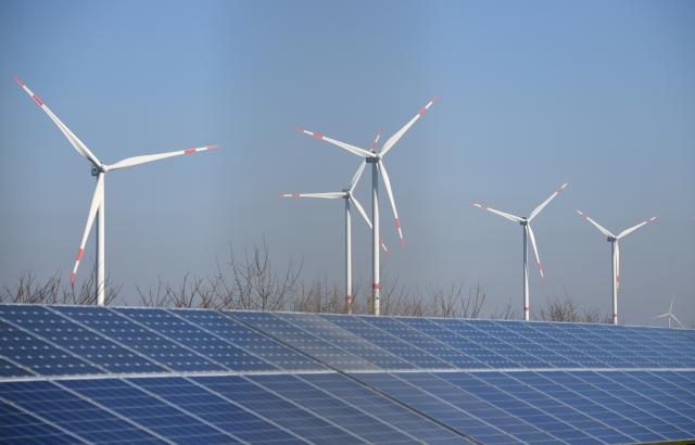 FILED - 27 February 2019, Schleswig-Holstein, Klixbuell: Wind power plants stand behind a solar power free-field plant in the Klixbuell solar park. Photo: Carsten Rehder/dpa