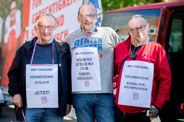 29 April 2026, Lower Saxony, Emden: Members of IG Metall wearing masks depicting German Chancellor Friedrich Merz, take part in a demonstration in the Stadtgarten in conjunction with the 14th National Maritime Conference (NMK). Photo: Hauke-Christian Dittrich/dpa