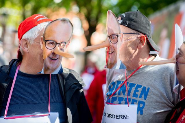 29 April 2026, Lower Saxony, Emden: Members of IG Metall wearing masks depicting German Chancellor Friedrich Merz, take part in a demonstration in the Stadtgarten in conjunction with the 14th National Maritime Conference (NMK). Photo: Hauke-Christian Dittrich/dpa