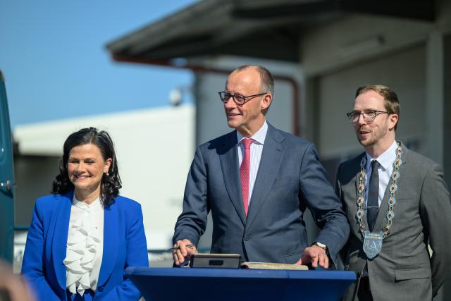 29 April 2026, Lower Saxony, Moormerland: German Chancellor Friedrich Merz signs the town's Golden Book, next to Gitta Connemann (L), Government Commissioner for Small and Medium-Sized Enterprises, and Hendrik Schulz (R), Mayor of Moormerland, during a tour of the Akkermann Transporte GmbH premises. Photo: Izabela Mittwollen/dpa