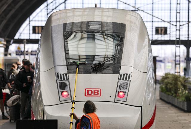 28 April 2026, Saxony, Leipzig: A railroad employee cleans the windshield on an ICE-4 arriving at Leipzig Central Station. Around 400 ICE trains are on the rails every day throughout Germany. To keep the trains clean for more than 370,000 passengers a day, Deutsche Bahn has launched an immediate program for more comfort in long-distance transport. Photo: Jan Woitas/dpa