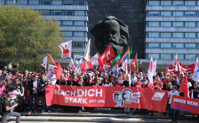 FILED - 01 May 2025, Chemnitz: FILE PHOTO - People hold flags as they take part in a rally organized by the German Trade Union Confederation (DGB) to mark the International Workers' Day in Chemnitz. Photo: Sebastian Willnow/dpa