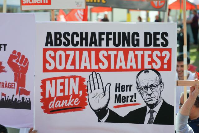 01 May 2026, Hesse, Herborn: A demonstration poster with the inscription "Abolition of the welfare state? No, thank you Mr. Merz!" can be seen at the main DGB Hesse-Thuringia rally with Hesse DGB Chairman Rudolph and State Economics Minister Mansoori (SPD), among others, in the city park. The occasion is a nationwide trade union rally to mark International Workers' Day. Photo: Sascha Ditscher/dpa