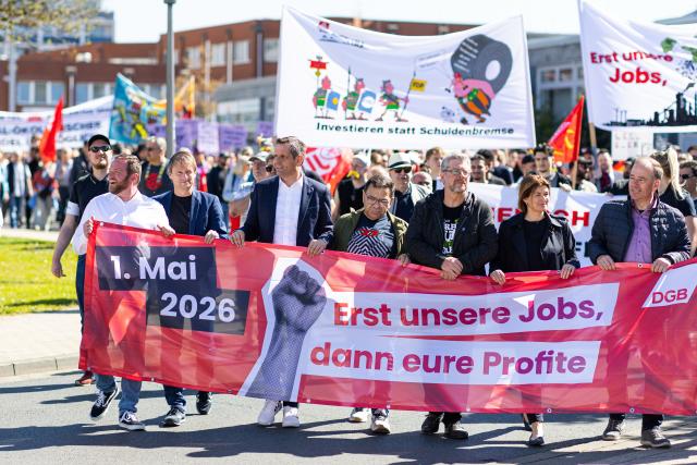 01 May 2026, Lower Saxony, Salzgitter: Olaf Lies (3-L), Minister President of Lower Saxony, holds a banner of the German Trade Union Confederation with the inscription: "May 1, 2026; First our jobs, then your profits" together with other participants. The occasion is a nationwide trade union rally to mark International Workers' Day. Photo: Michael Matthey/dpa