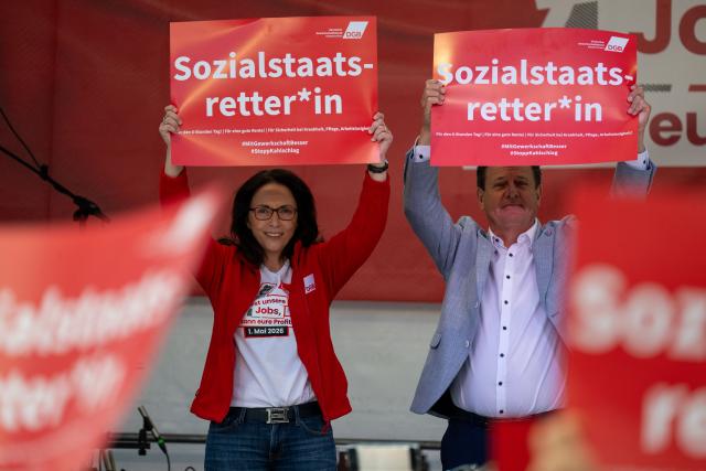01 May 2026, Bavaria, Nuremberg: DGB head Yasmin Fahimi and Stephan Doll, regional director of the German Trade Union Confederation for Middle Franconia, stand on a stage in Nuremberg and hold up signs reading "Welfare state savior". The occasion is a nationwide trade union rally to mark International Workers' Day. Photo: Pia Bayer/dpa