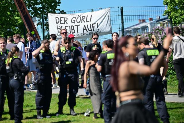 01 May 2026, Berlin: "Goerli stays open" is written on a poster in Goerlitzer Park on May 1. Police officers are in the foreground. Several demonstrations and events take place across Germany and in the city on May 1. Photo: Sebastian Christoph Gollnow/dpa