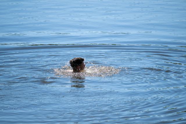 01 May 2026, Bavaria, Breitenguessbach: A man shakes his hair as he emerges from the water of a swimming lake. Photo: Pia Bayer/dpa