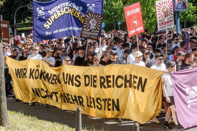 01 May 2026, Hamburg: People hold a banner reads "We can no longer afford the rich," at a demonstration calling for the redistribution of wealth. On May 1, several demonstrations and events are taking place across the country. Photo: Markus Scholz/dpa