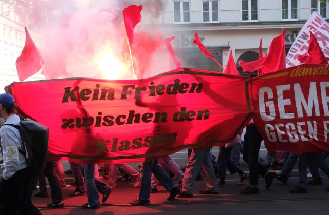 01 May 2026, Saxony, Leipzig: Participants in a left-wing demonstration march down a street carrying banners and setting off fireworks. On May 1, several demonstrations and events are taking place across the country. Photo: Sebastian Willnow/dpa