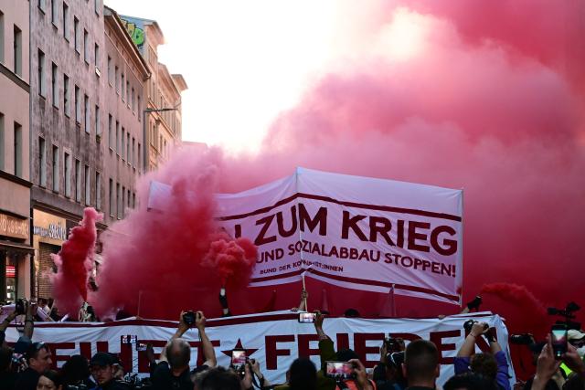 01 May 2026, Berlin: Participants in a left-wing demonstration march down a street carrying banners and setting off fireworks. On May 1, several demonstrations and events are taking place across the country. Photo: Sebastian Gollnow/dpa