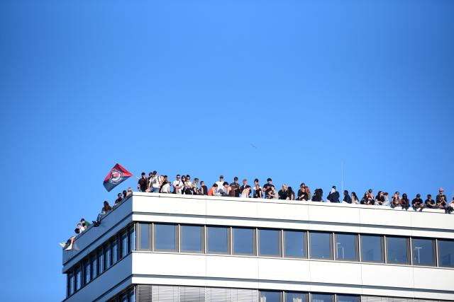 01 May 2026, Hamburg: Participants stand on the roof of a building during a demonstration with the slogan "War and crisis are systemic. United as a class: Fight for socialism!". On May 1, several demonstrations and events will take place across the country. Photo: Daniel Bockwoldt/dpa