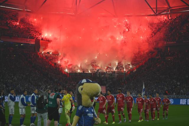02 May 2026, North Rhine-Westphalia, Gelsenkirchen: Duesseldorf set off pyrotechnics in the background as the two teams greet each other before the German 2nd Bundesliga soccer match between FC Schalke 04 and Fortuna Duesseldorf at Veltins Arena. Photo: Bernd Thissen/dpa - WICHTIGER HINWEIS: Gemäß den Vorgaben der DFL Deutsche Fußball Liga bzw. des DFB Deutscher Fußball-Bund ist es untersagt, in dem Stadion und/oder vom Spiel angefertigte Fotoaufnahmen in Form von Sequenzbildern und/oder videoähnlichen Fotostrecken zu verwerten bzw. verwerten zu lassen.