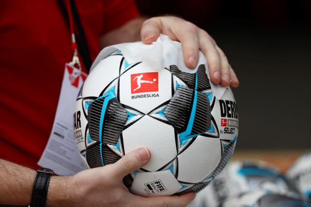 FILED - 14 June 2020, Rhineland-Palatinate, Mainz: A ball boy disinfects a game ball prior to the start of the 2020 German Bundesliga soccer match between FSV Mainz 05 and FC Augsburg at the Opel Arena. Photo: Kai Pfaffenbach/reuters/Pool/dpa - IMPORTANT NOTICE: DFL and DFB regulations prohibit any use of photographs as image sequences and/or quasi-video.