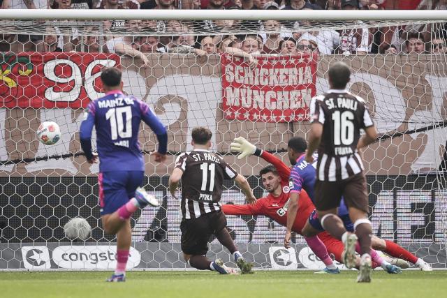 03 May 2026, Hamburg: Mainz' Phillipp Mwene  (R) scores his side's second goal against St. Pauli goalkeeper Nikola Vasilj during the German Bundesliga soccer match between the FC St. Pauli and FSV Mainz 05 at the Millerntor Stadium. Photo: Christian Charisius/dpa - IMPORTANT NOTICE: DFL and DFB regulations prohibit any use of photographs as image sequences and/or quasi-video.