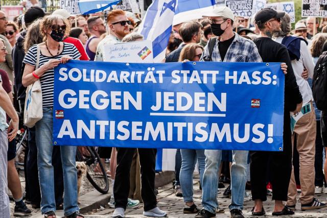 03 May 2026, Berlin: Participants hold a banner reading "Solidarity instead of hate" and wave Israeli flags during the vigil "Against all anti-Semitism - solidarity with Jews" in Berlin, after anti-Semitic lettering was seen on a residential building. Photo: Carsten Koall/dpa