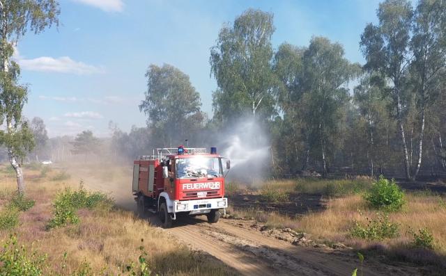 16 August 2024, Brandenburg, Jueterbog: The fire department battles a forest fire in Jueterbog, where a blaze has been burning on a former military training site contaminated with ammunition since Friday. Photo: Cevin Dettlaff/dpa