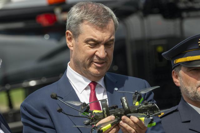 04 May 2026, Bavaria, Erding: Markus Soeder (R), Prime Minister of Bavaria, holds a small drone during the opening of the Drone Competence and Defense Center. Photo: Peter Kneffel/dpa