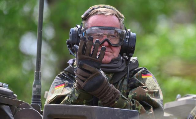 04 May 2026, Lower Saxony, Munster: German Minister of Defence, Boris Pistorius (L), puts on gloves before taking a ride on a German Military (Bundeswehr) tank. Photo: Philipp Schulze/dpa