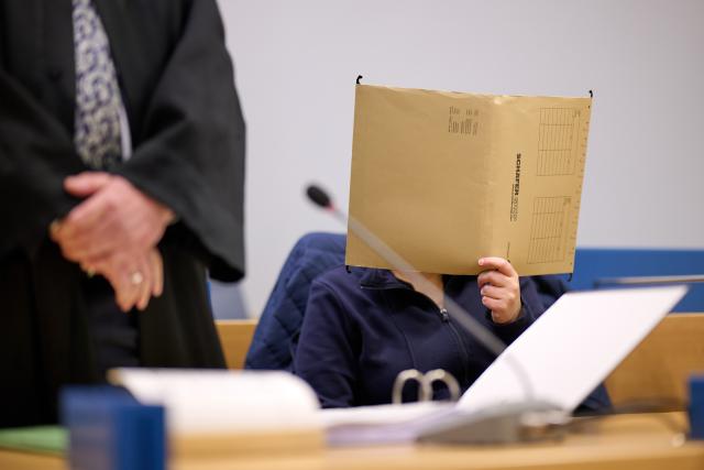 FILED - 07 January 2026, North Rhine-Westphalia, Siegen: FILE PHOTO - The defendant hides her face behind a file, during her trial for allegedly keeping her daughter confined in her grandparents' home, hidden and completely cut off from the outside world for seven years. Photo: Bernd Thissen/dpa