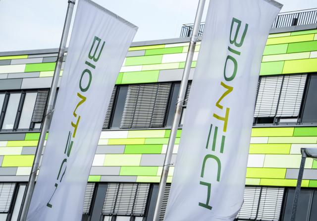 PRODUCTION - 21 April 2026, Rheinland-Pfalz, Mainz: The flags of the pharmaceutical company Biontech are fluttering in the wind in front of the company's headquarters. Photo: Andreas Arnold/dpa